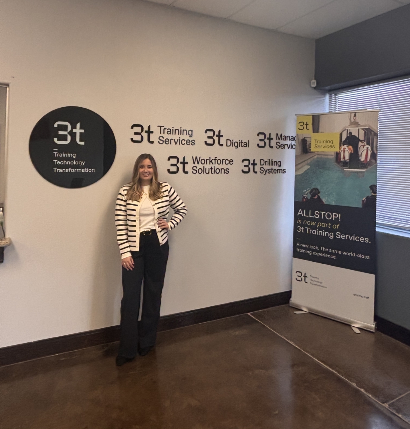 Bid writer Danielle standing against a wall with 3t branding