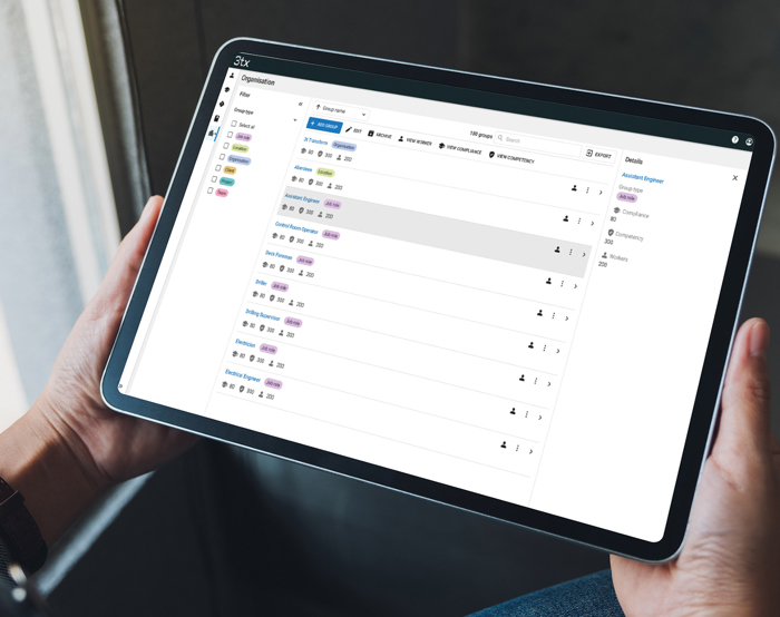 Person holding a tablet displaying a task management application with a list of tasks and their statuses.