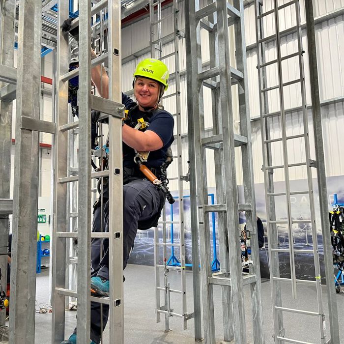 3t instructor with a neon helmet climbing up a ladder for GWO training.