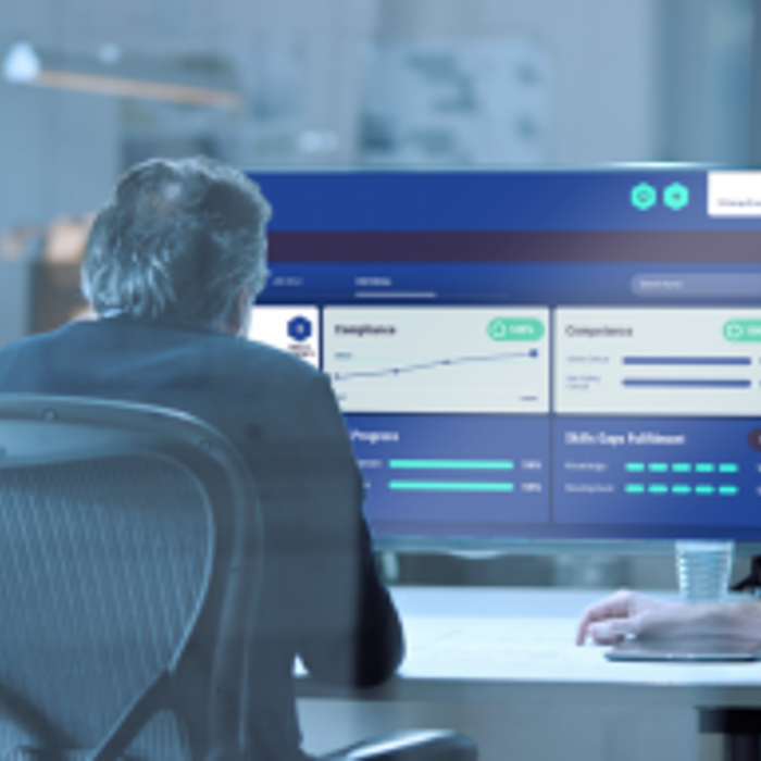 Four people in an office are sitting around a table, focusing on a digital screen displaying graphs and metrics.