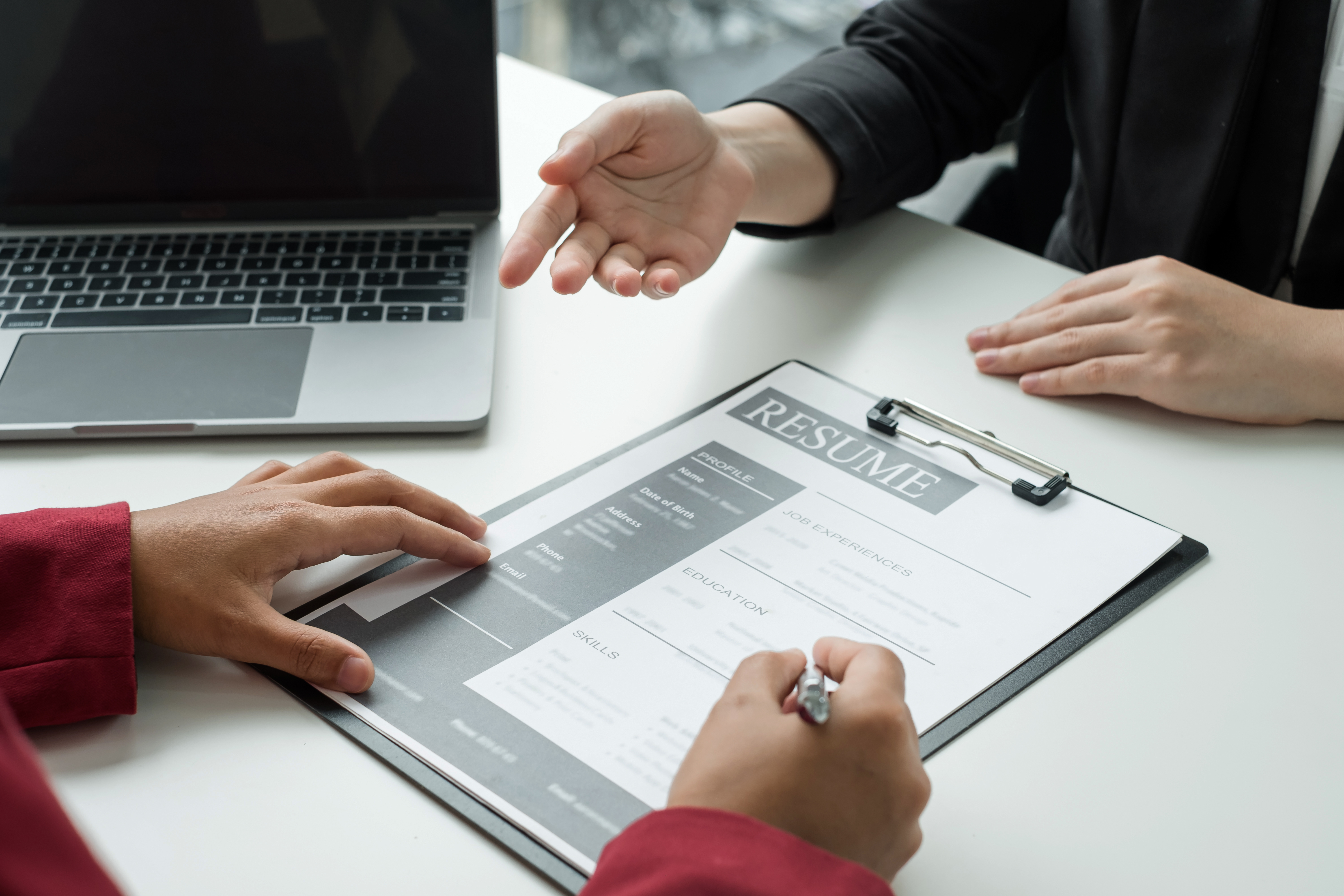 شخص يرتدي سترة عالية الوضوح وقبعة صلبة ويستخدم جهاز كمبيوتر محمول في بيئة صناعية.