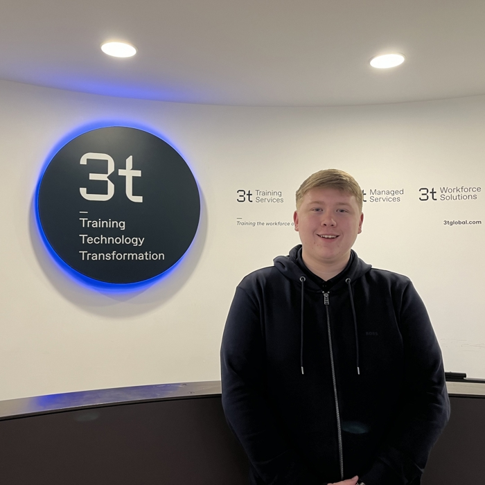 A person stands in front of a reception desk with a sign reading "3t: Training, Technology, Transformation" on the wall, ready to embark on a journey of professional training and growth.