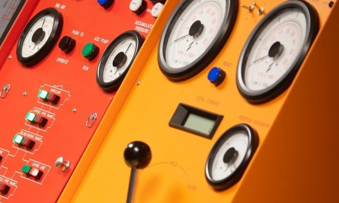 Close-up of two control panels, one red and one yellow, featuring various dials, switches, buttons, and gauges, indicating instrumentation for machinery or technical equipment.
