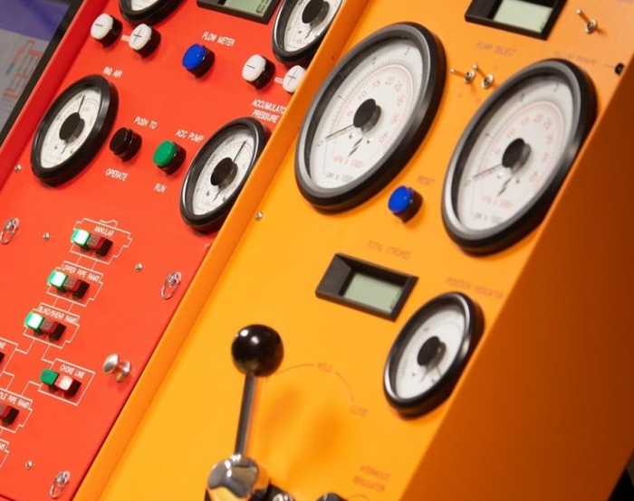 Close-up of two control panels, one red and one yellow, featuring various dials, switches, buttons, and gauges, indicating instrumentation for machinery or technical equipment.